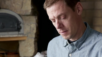 Man preparing wild turkey apple sausage in kitchen with stone oven behind him