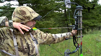 Hunter in camouflage drawing a compound bow with nocked arrow, MeatEater logo overlay