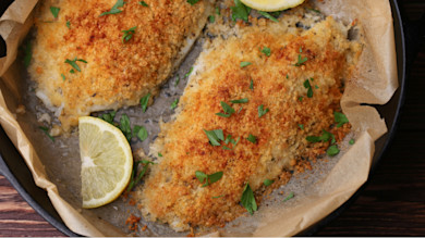 Breaded catfish fillets baked in skillet with parsley and a lemon wedge