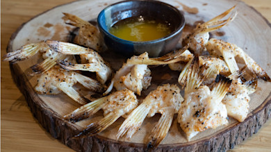 Walleye wings grilled on round wood board with small bowl of melted butter