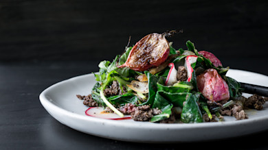 Juniper-spiced ground venison with charred radishes and sautéed greens on a white plate