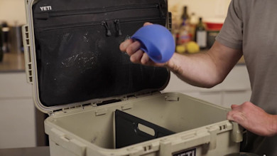 Open YETI cooler with person holding a blue collapsible bowl