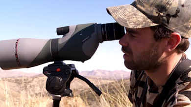 Hunter using Vortex spotting scope on tripod in dry hills, MeatEater logo overlay