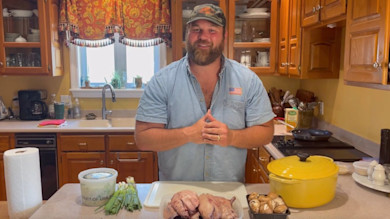 Man in kitchen preparing whole ducks, mushrooms, scallions, and yellow Dutch oven on counter