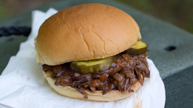 Pulled roast barbecue sandwich with pickle slices on a soft bun