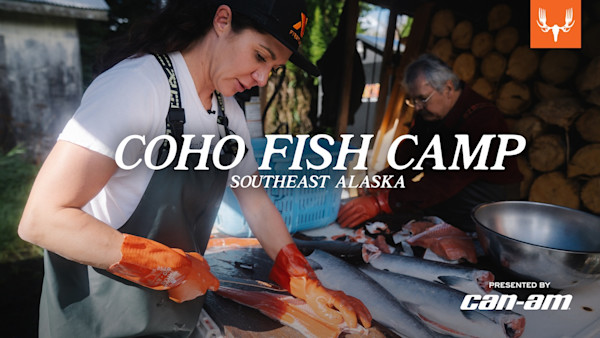 Woman filleting salmon at table, two people in shelter; text overlay: COHO FISH CAMP SOUTHEAST ALASKA