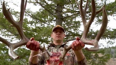 Hunter holding large antlers showing exposed pedicle and blood
