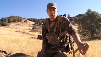 Steven Rinella sitting in dry California grass wearing camouflage and a backpack
