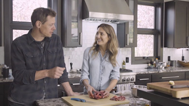 Woman and man cleaning a raw heart on a kitchen cutting board