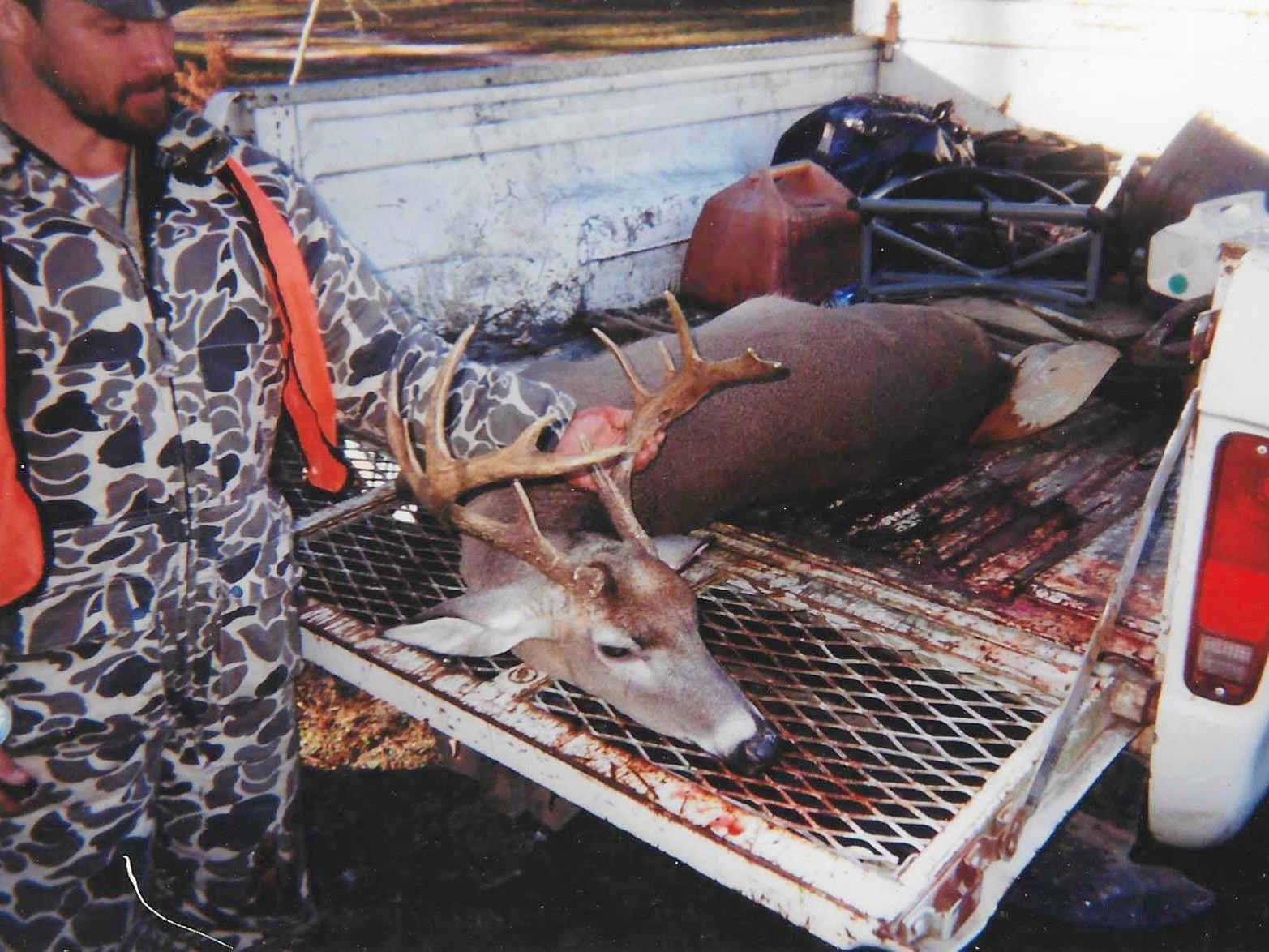 11-point buck in pickup truck bed with hunter holding its antlers