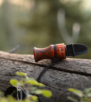Elk call with wood-grain handle and orange band reading MEATEATER and Phelps