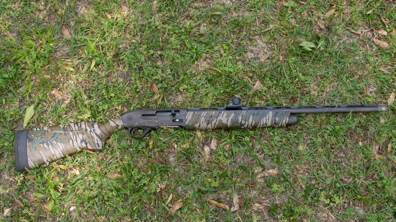 Semi-automatic shotgun with tiger-striped camouflage stock and mounted red-dot sight