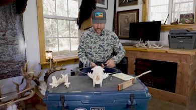 Man scoring a bear skull at a workbench wearing Bear Grease cap