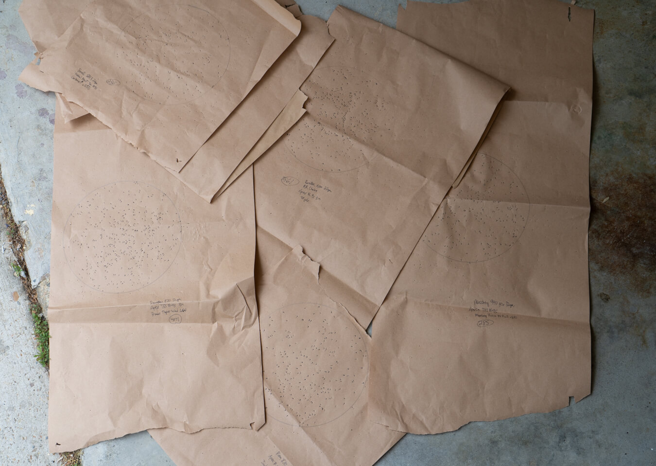Brown paper targets with circular pellet patterns spread on concrete floor