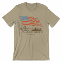 Tan T-shirt with waving U.S. flag and man riding an elk; reads "250 YEARS OF USA" and "MEATEATER"