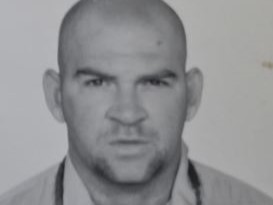 Bald man facing camera in black-and-white headshot with neutral expression