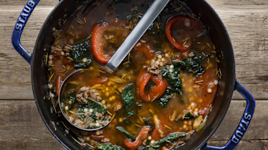 Dutch oven of ground-venison and red pepper soup with kale, couscous and a ladle; 'STAUB' on handle