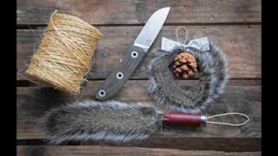 Squirrel-tail Christmas ornaments with pinecone and silver bow, knife and twine on wood