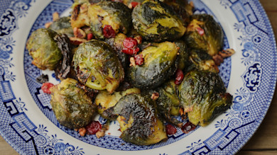 Smashed roasted Brussels sprouts with dried cranberries and chopped walnuts on blue plate