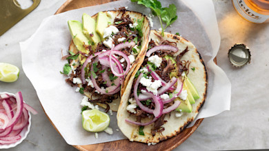 Two venison carnitas tacos with avocado, pickled red onion, queso and lime