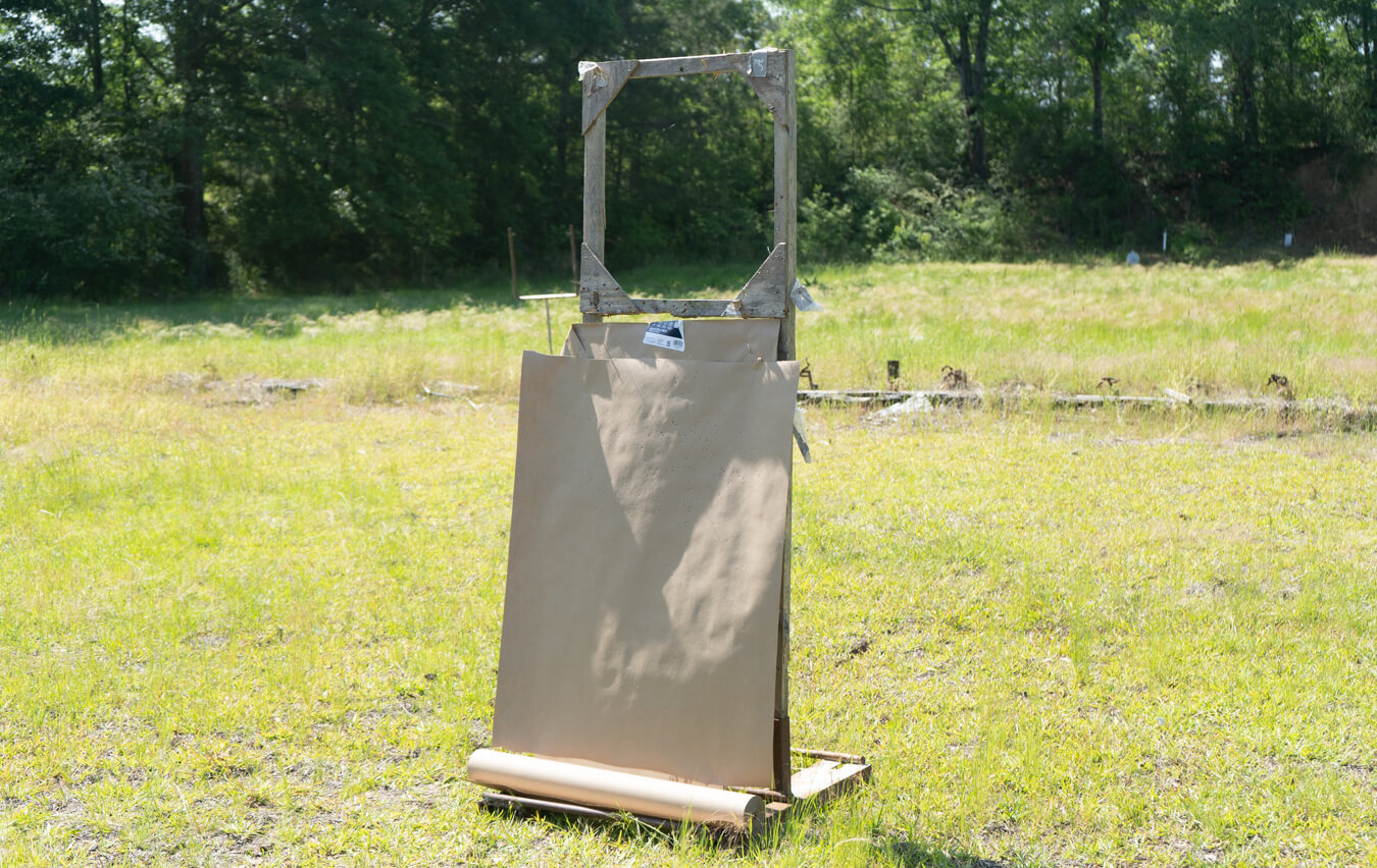 Wooden target stand with kraft paper target roll on grassy shooting range
