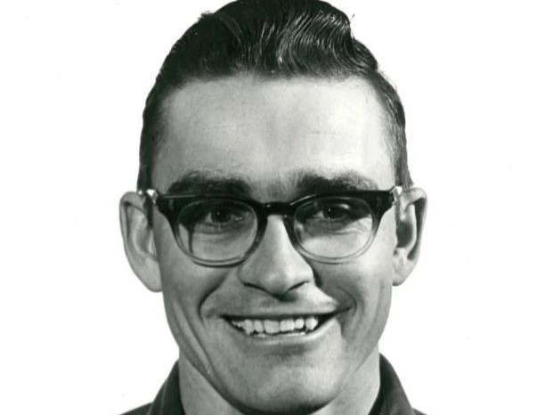 Smiling man with dark horn-rimmed glasses in black-and-white headshot
