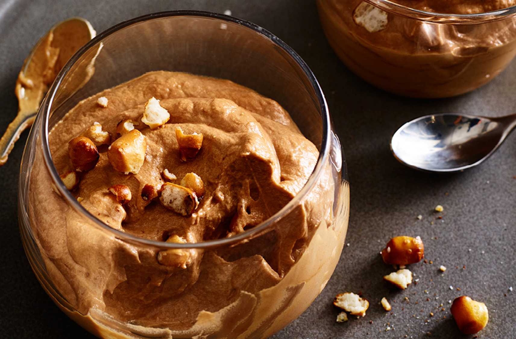 Glassses filled with caramel chocolate mouse topped with pretzel crumbs 