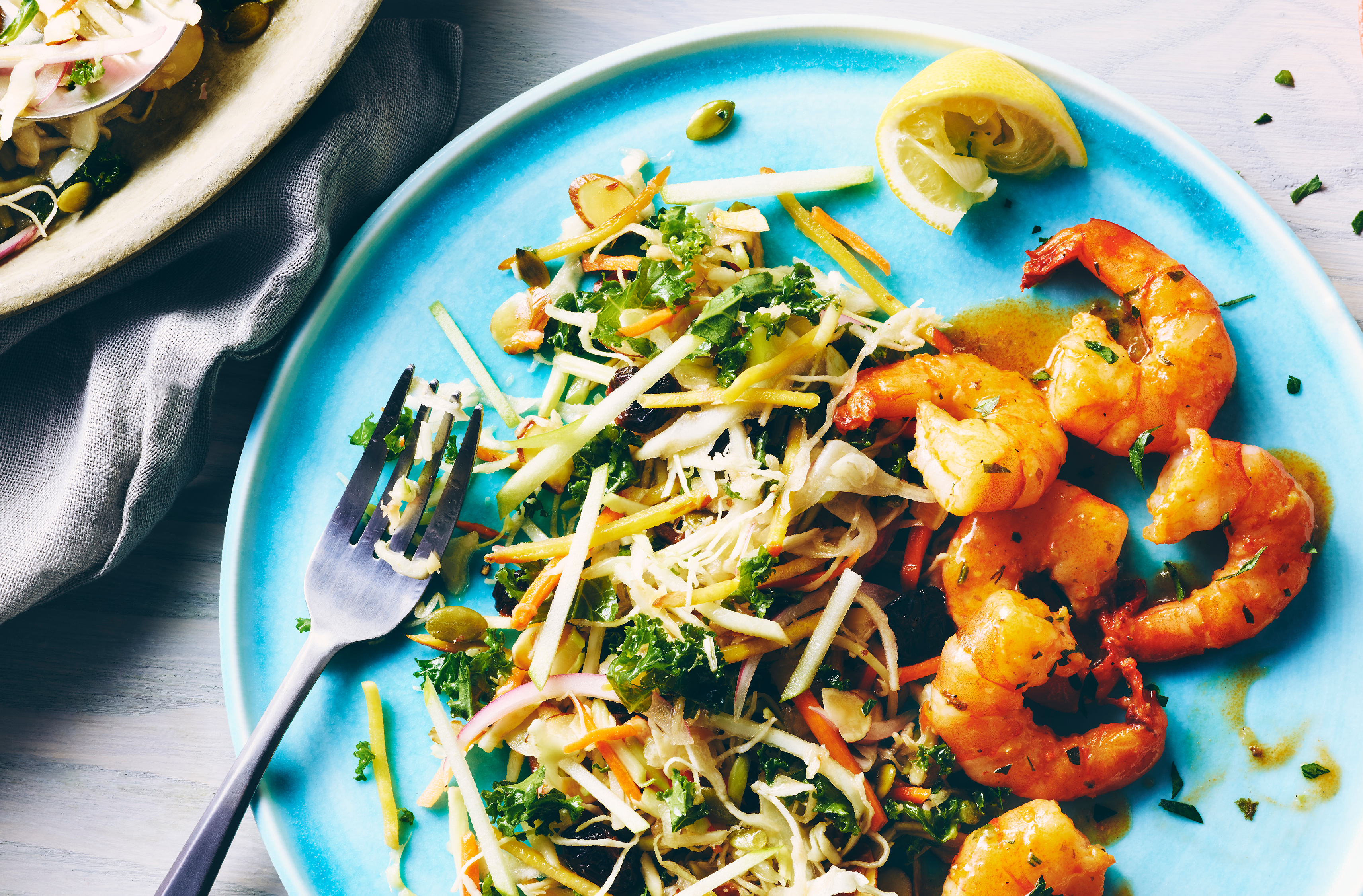 Sur une assiette, une salade de betteraves jaunes, de pommes et de fines herbes en à-côté avec six crevettes