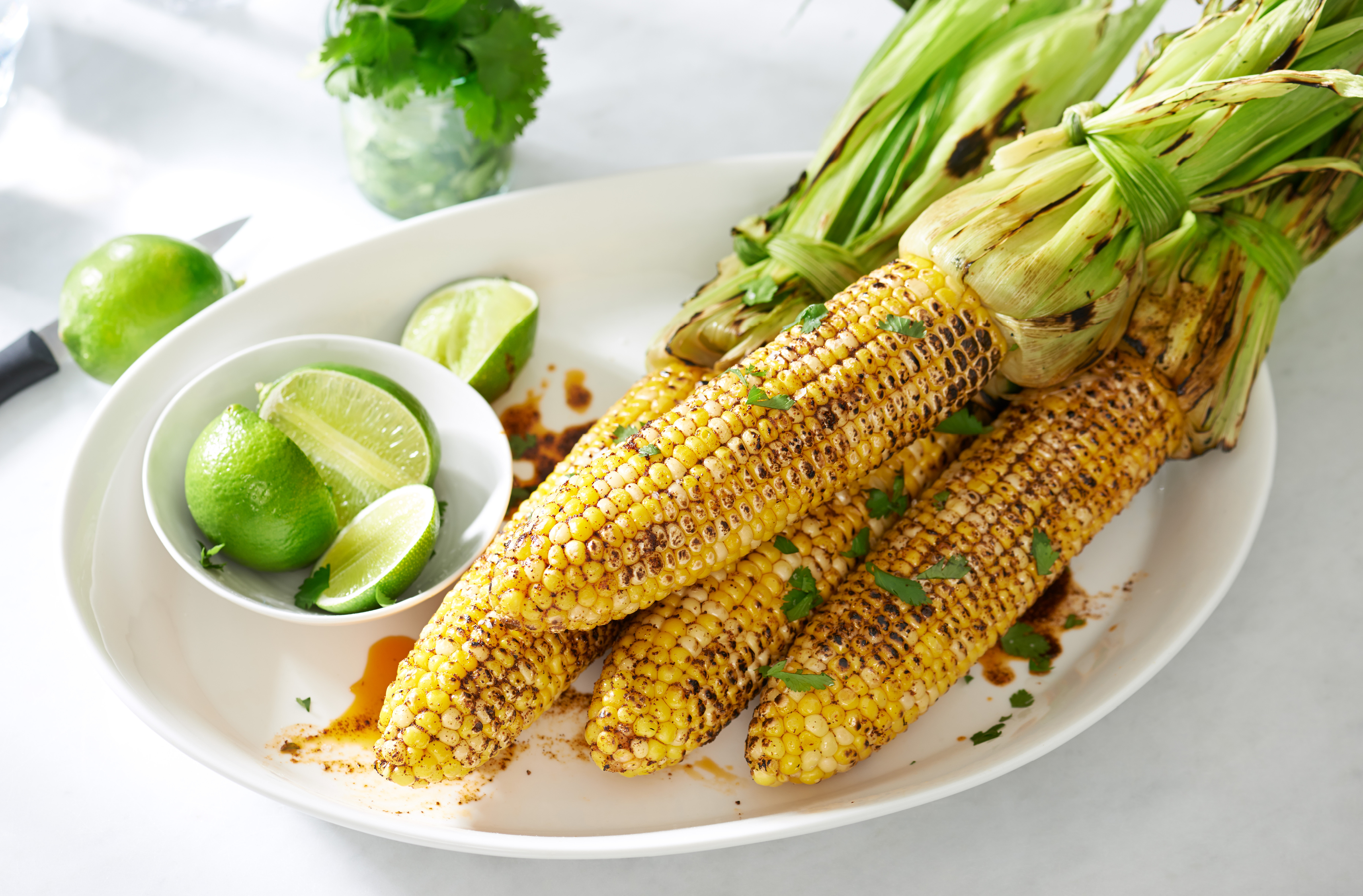 A platter with 4 ears of chili-seasoned, coconut oil-basted grilled corn

