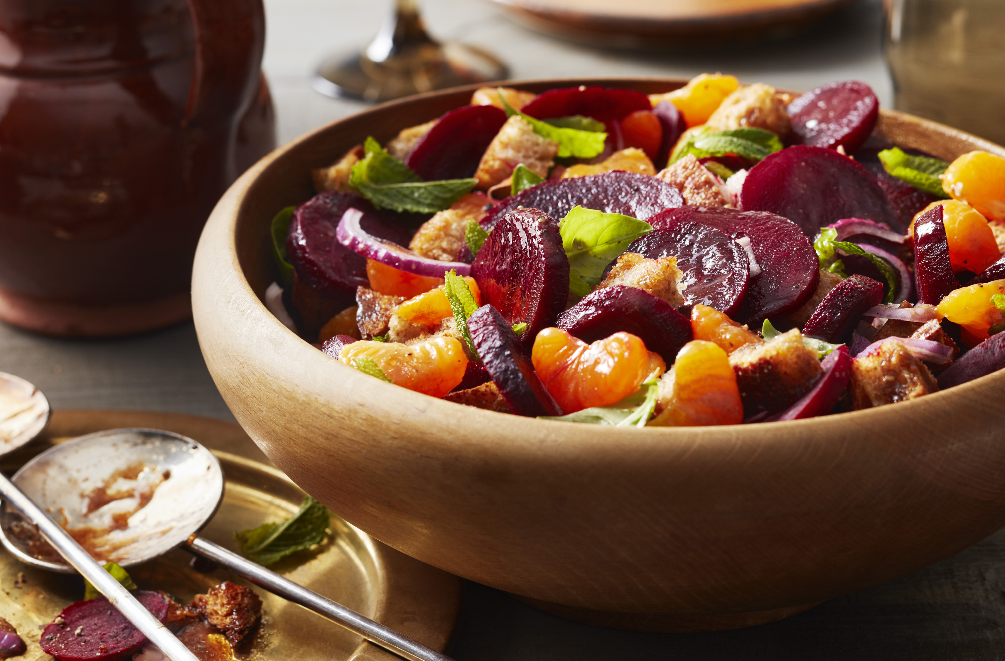 Beet salad with mandarin orange segments and herbs in a wooden bowl
