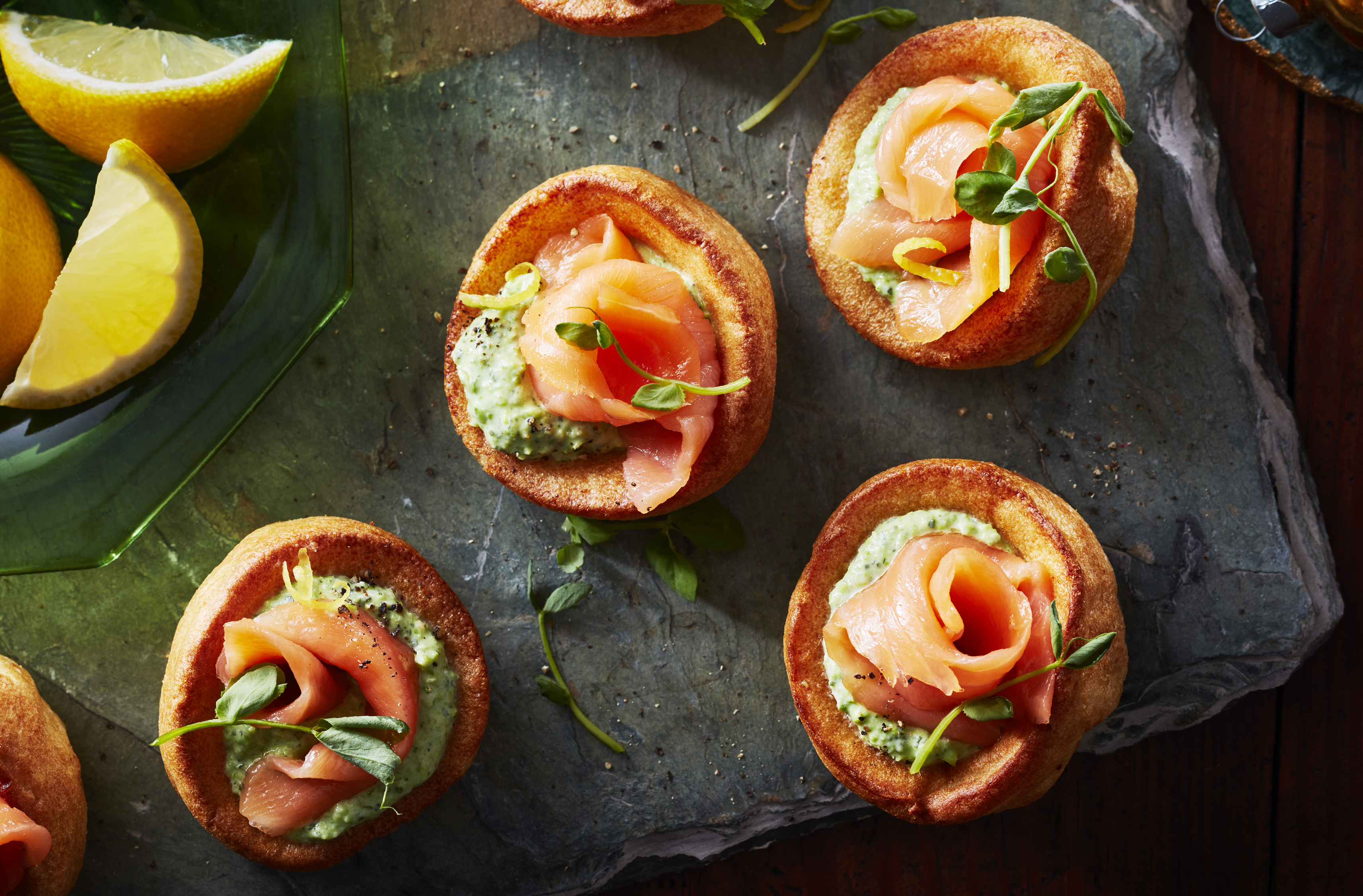 Lemon wedges stand beside smoked salmon rosettes on baked pastry rounds
