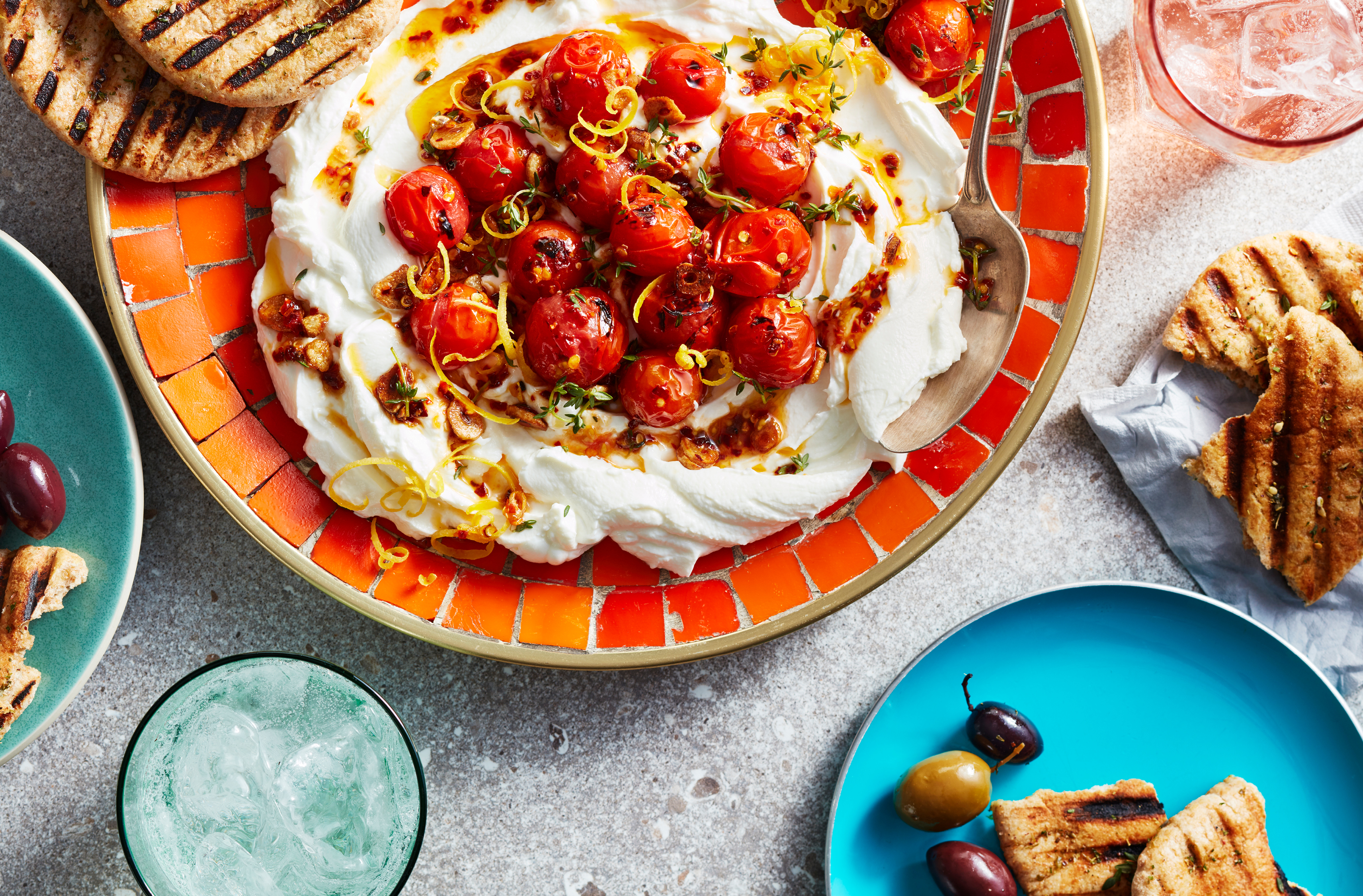 Charred axiany tomatoes nestled into a bed of plain skyr yogurt