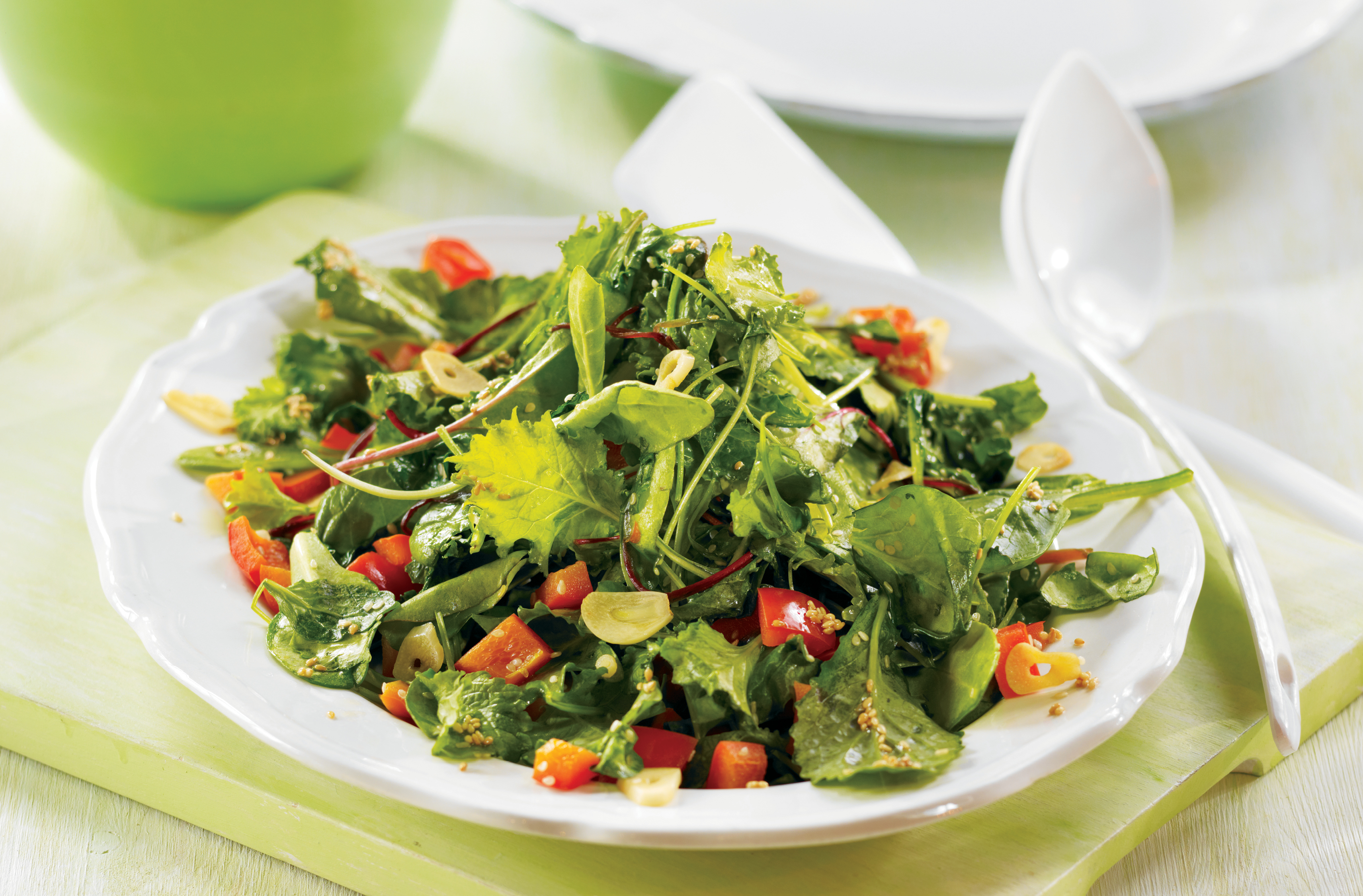 Une salade de légumes-feuilles sautés avec poivrons rouges, ail et graines de sésame dans un bol