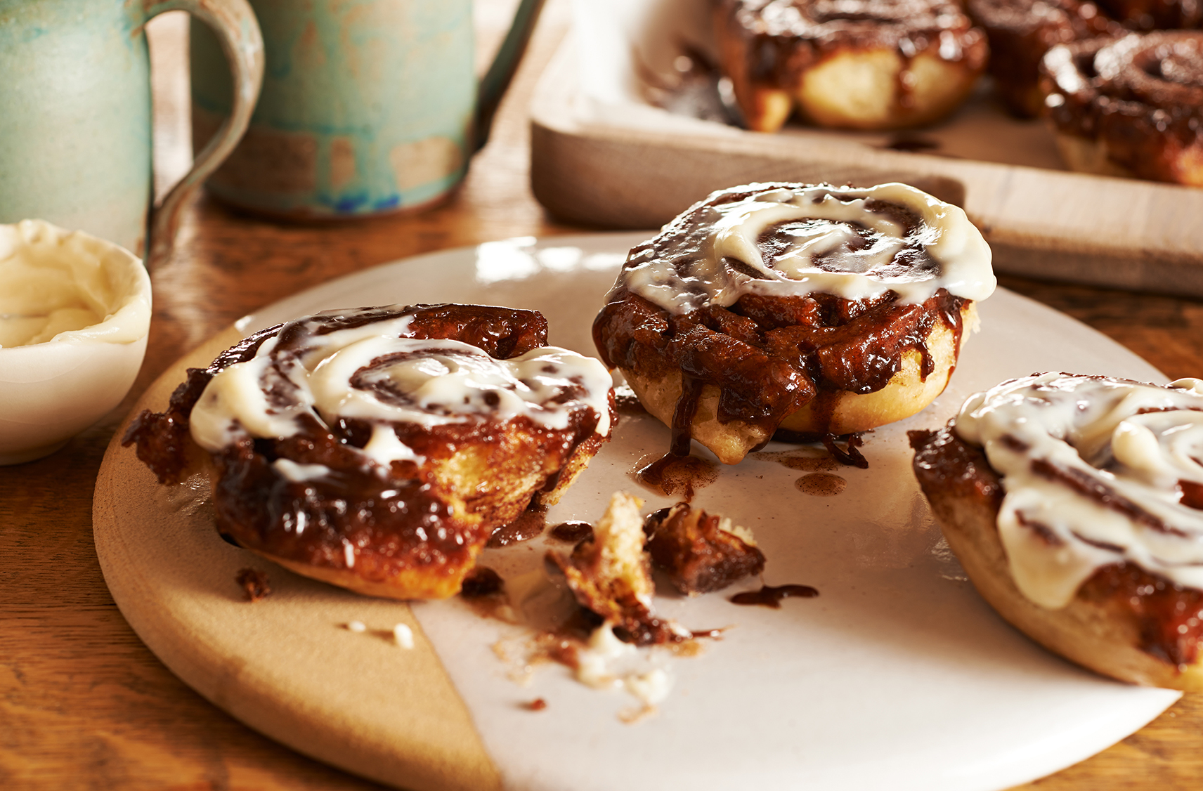 Two freshly baked and sticky cinnamon buns topped with white icing