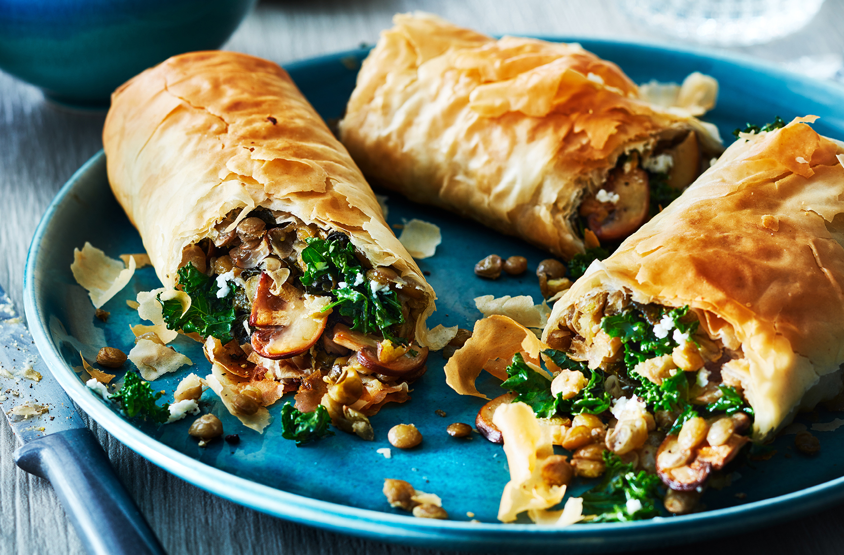 three strudels stuffed with savoury kale and mushroom mixture.  served on a blue plate