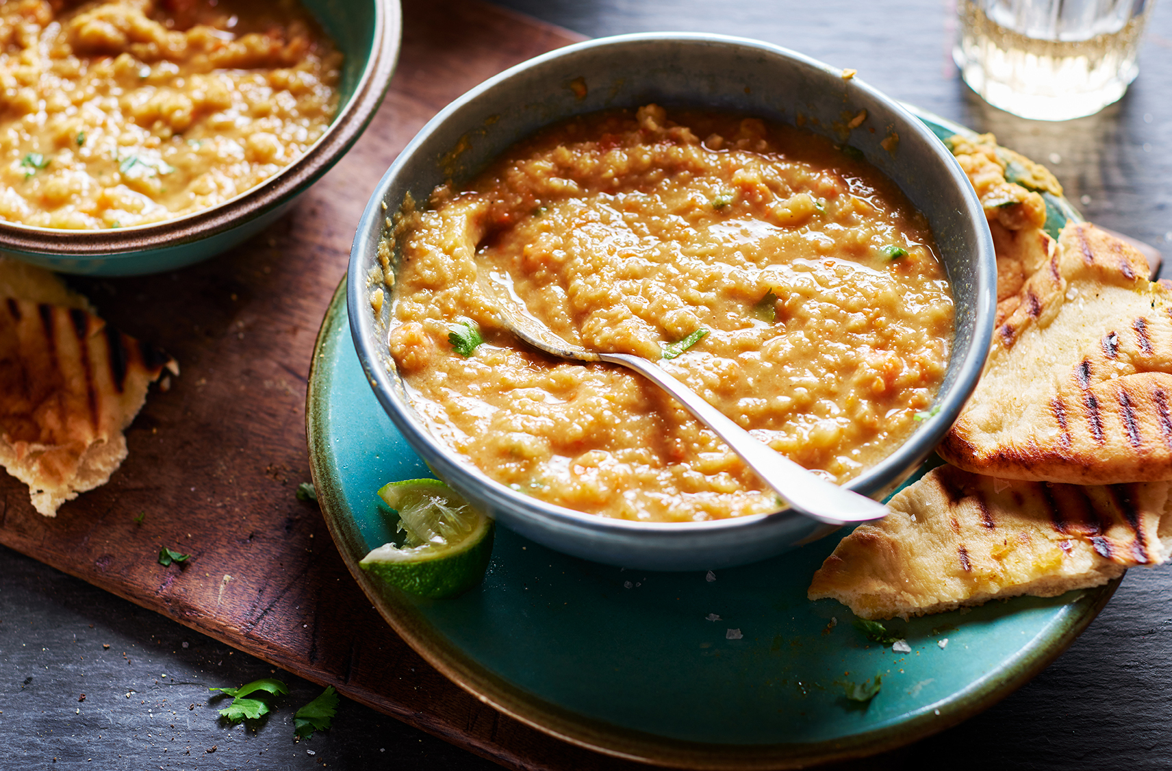 A bowl of creamy, yet textured, orange lentil soup garnished with coriander leaves