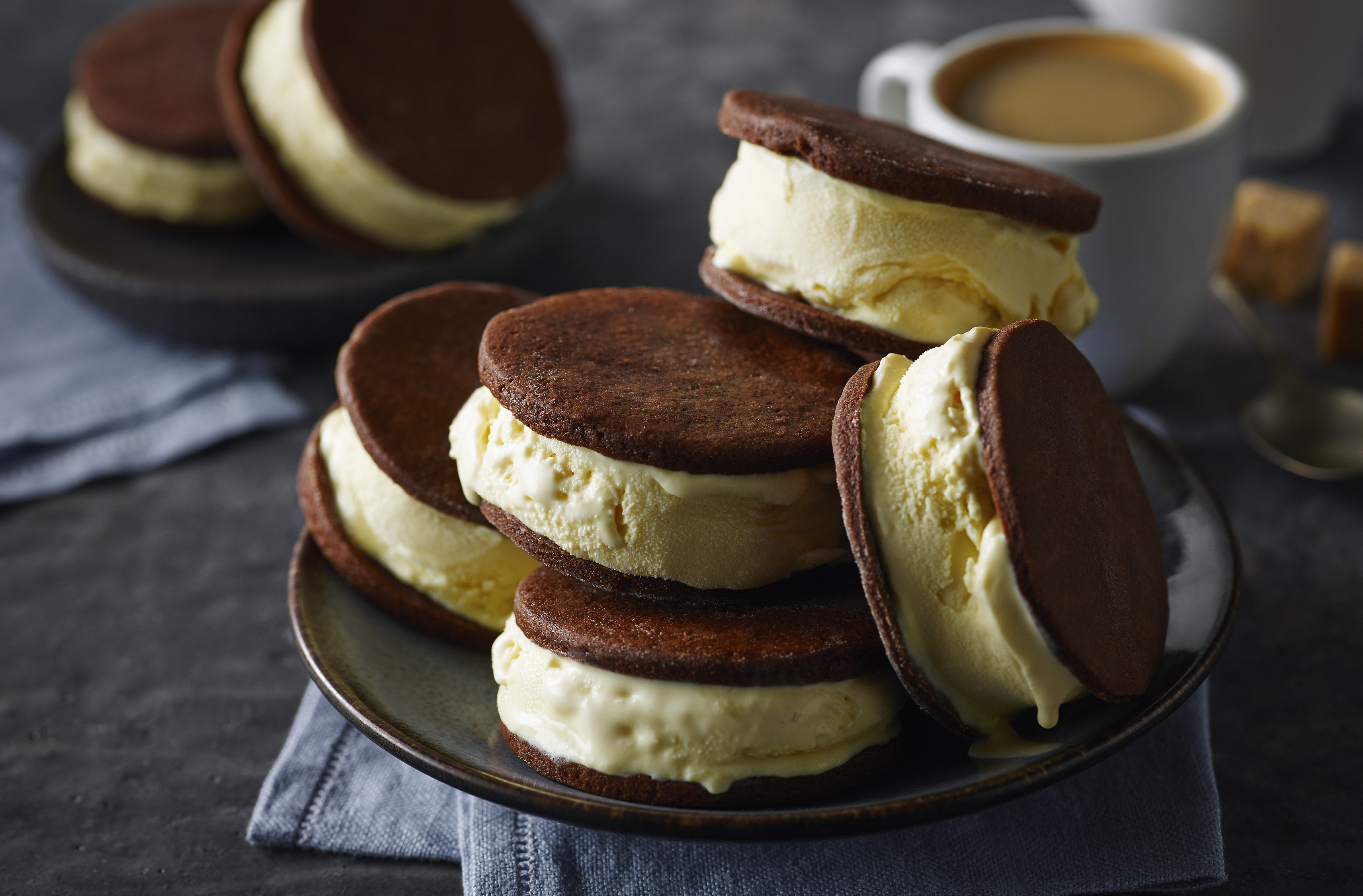 Ice cream sandwiches made with chocolate cookies and vanilla ice cream.  5 of them stacked and placed on a serving platter