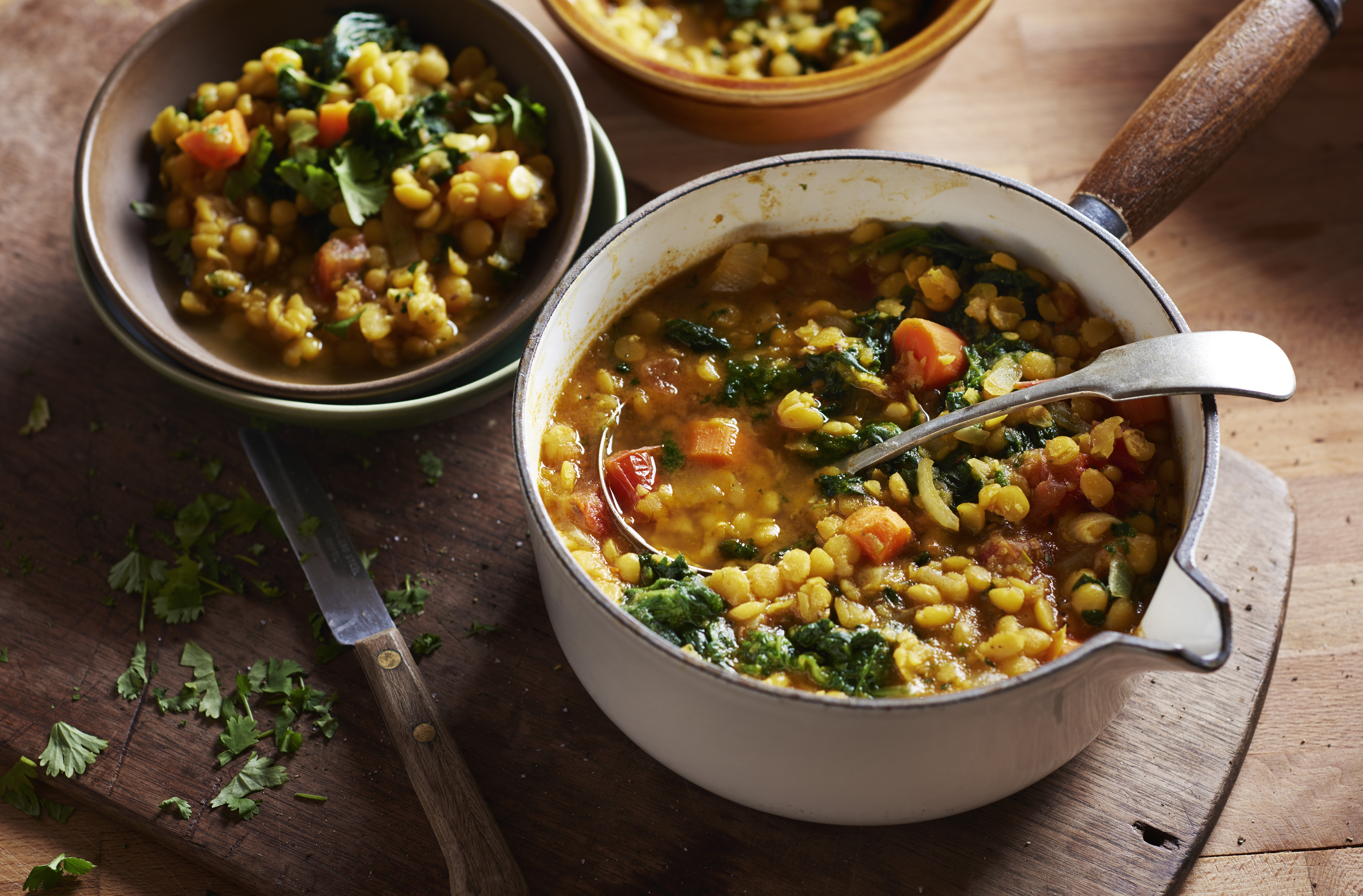 A cast iron pot filled with colourful pea soup and wilted spinach
