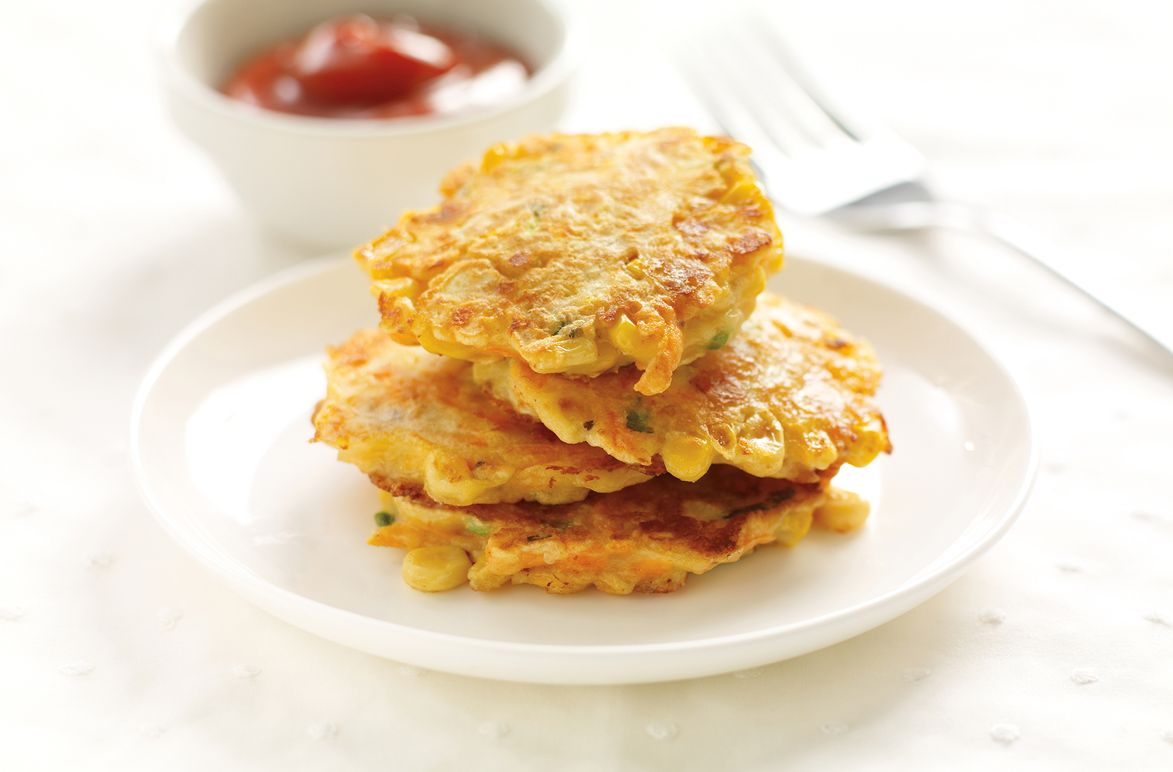 A stack of 4 hotcakes packed with carrots, corn, Cheddar & green onions