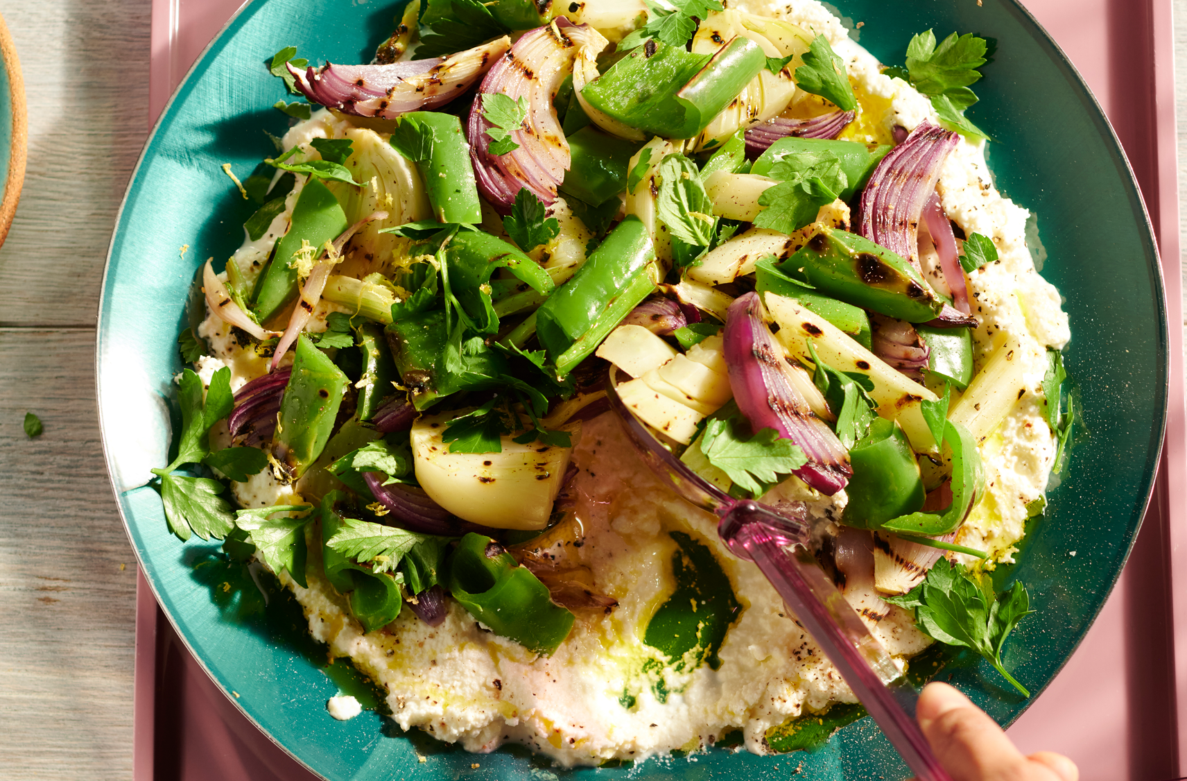 A turquoise platter with ricotta, grilled green peppers, red onion, fennel and fresh herbs.