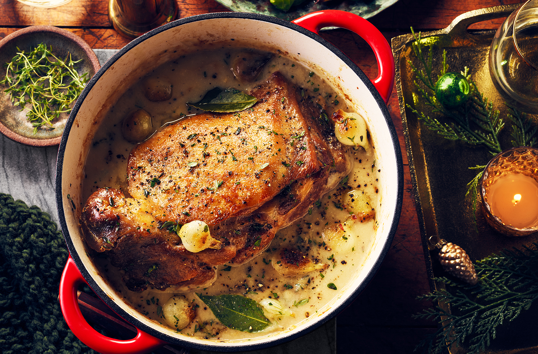 A casserole dish cradles crisped pork shoulder with herbs and a creamy sauce