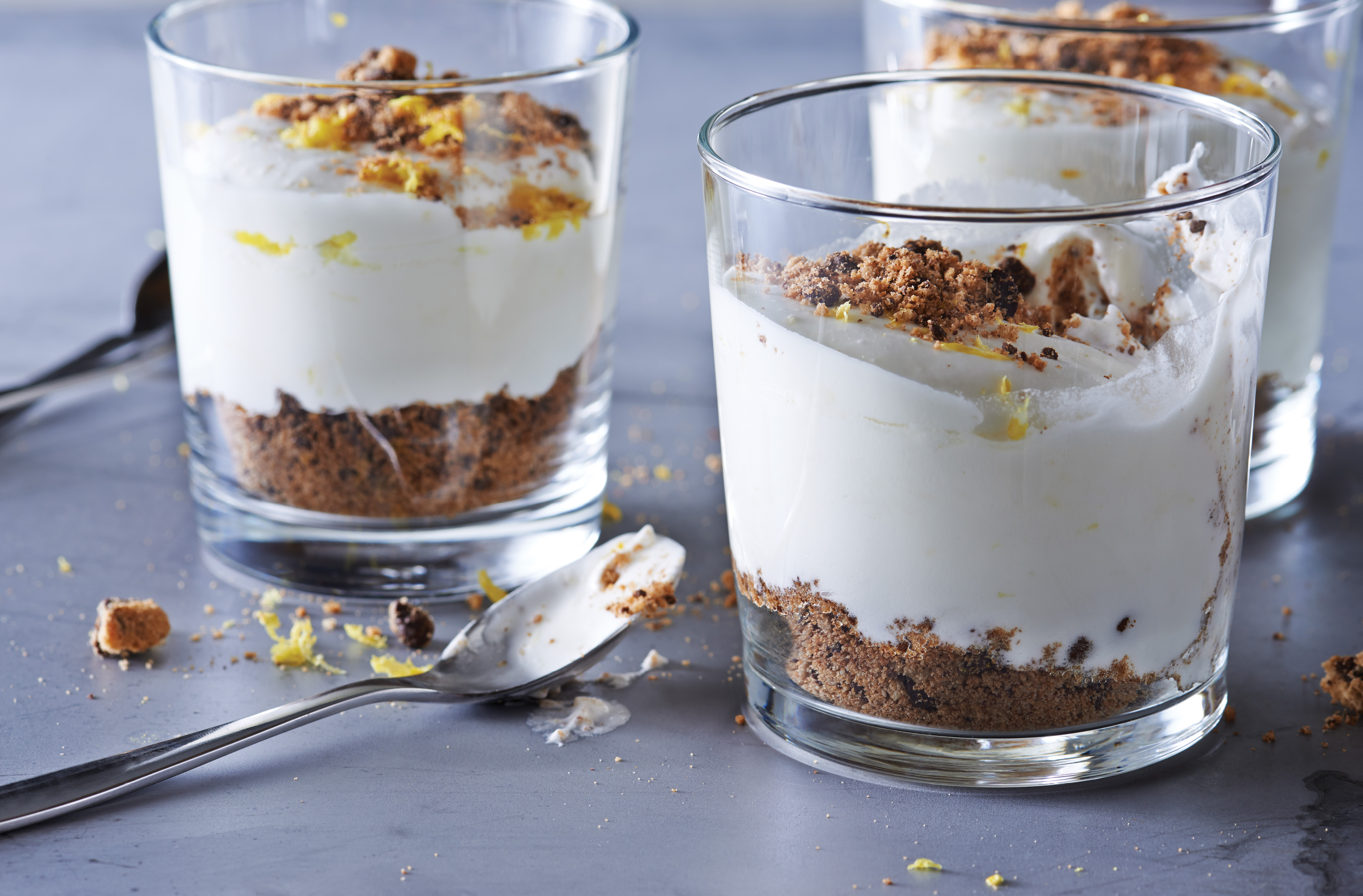 Un dessert mousseux dans un verre avec des biscuits émiettés au fond et sur le dessus