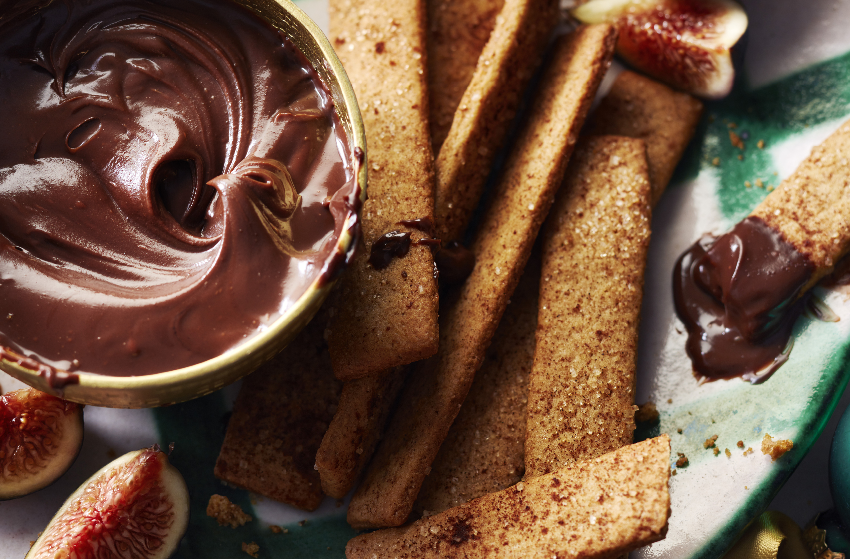 Spiced cookie sticks served with chocolate ganache on a plate
