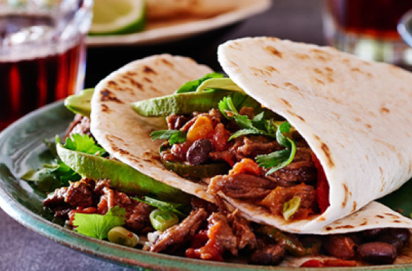 Deux tortillas souples remplies de lanières assaisonnées de bœuf mijoté et de légumes.