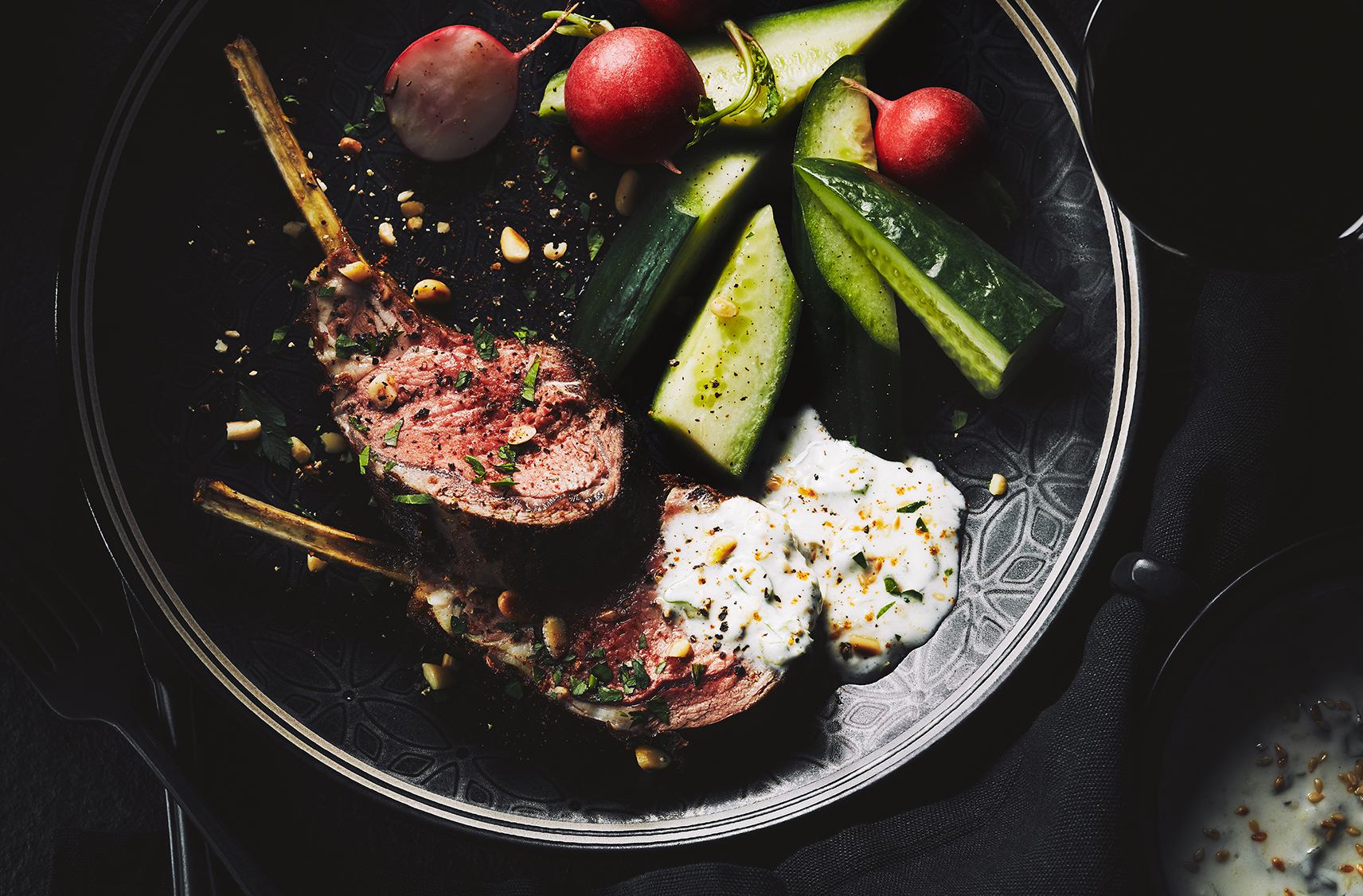 Pot containing a lamb dish with cucumbers and cherry tomatoes on the side 
