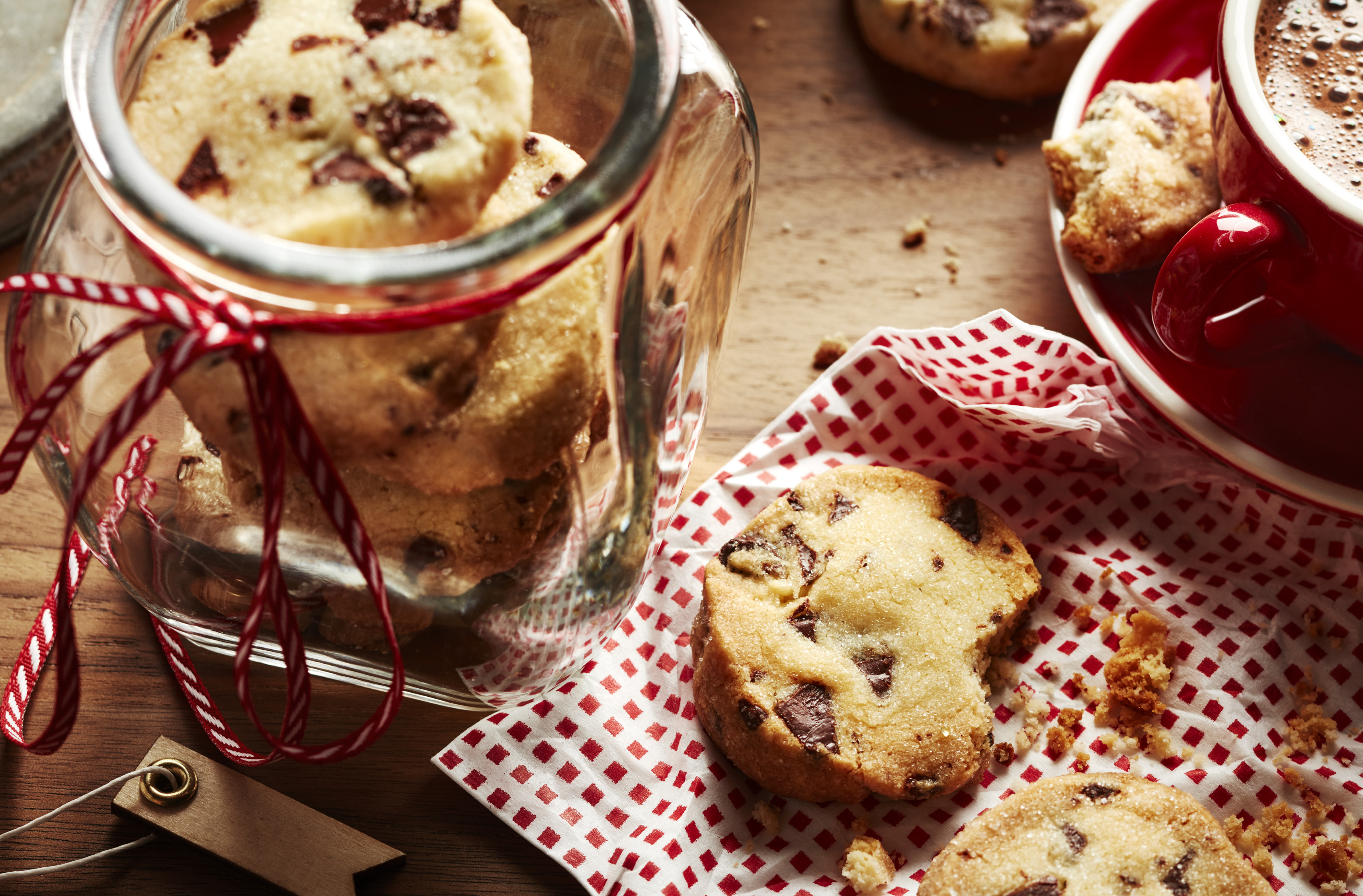 Mint chocolate chunk shortbread cookies in a cookie jar.  One cookie on napkin with a bite taken out of it.