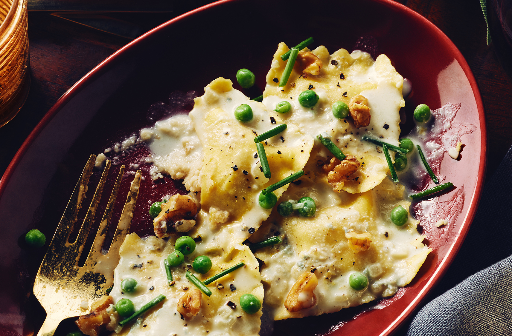 Cauliflower-stuffed pasta in a cream sauce topped with green peas and chive
