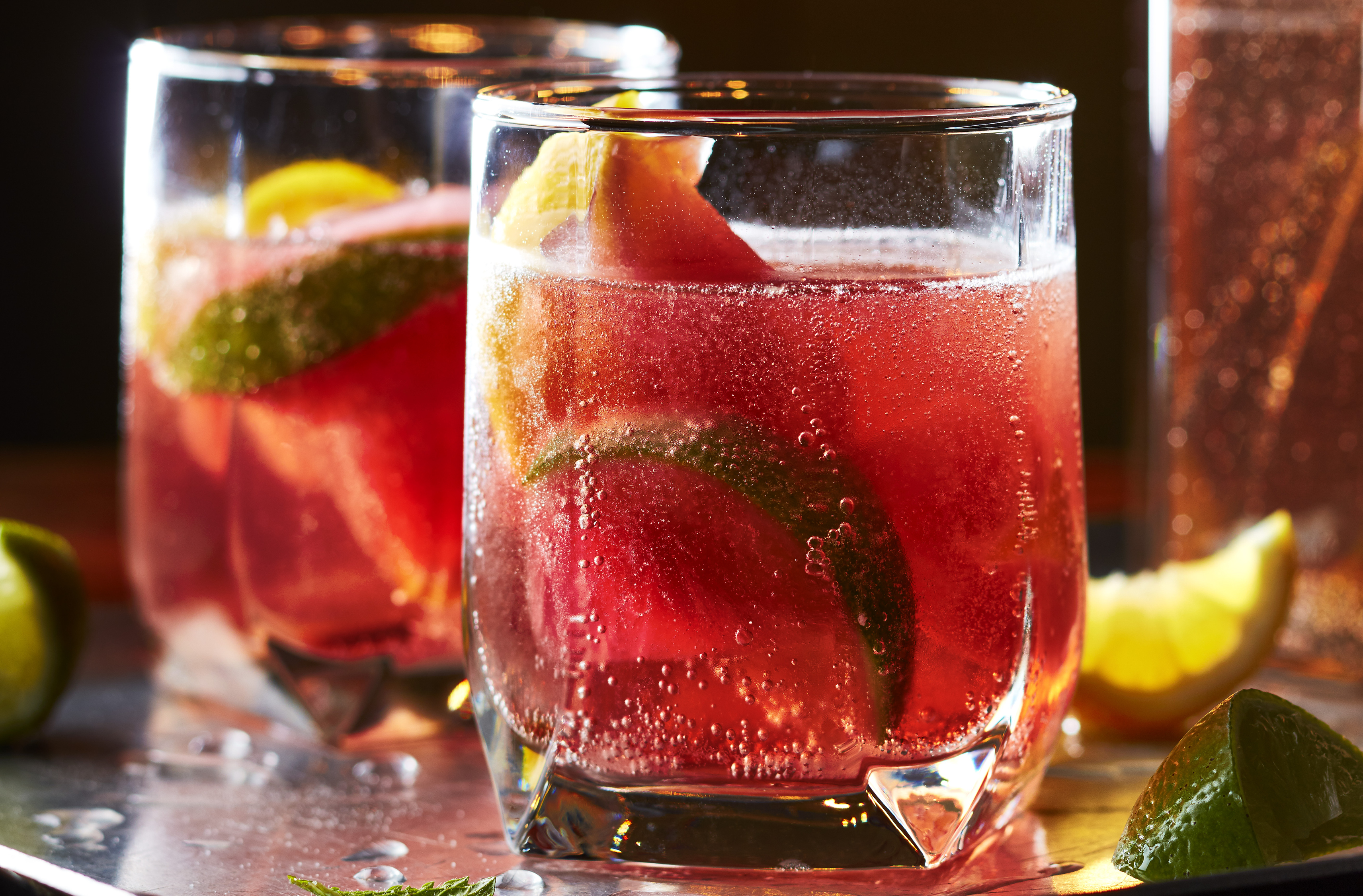 Two glasses of Ginger Hibiscus Sparkling Punch with slices of lime inside