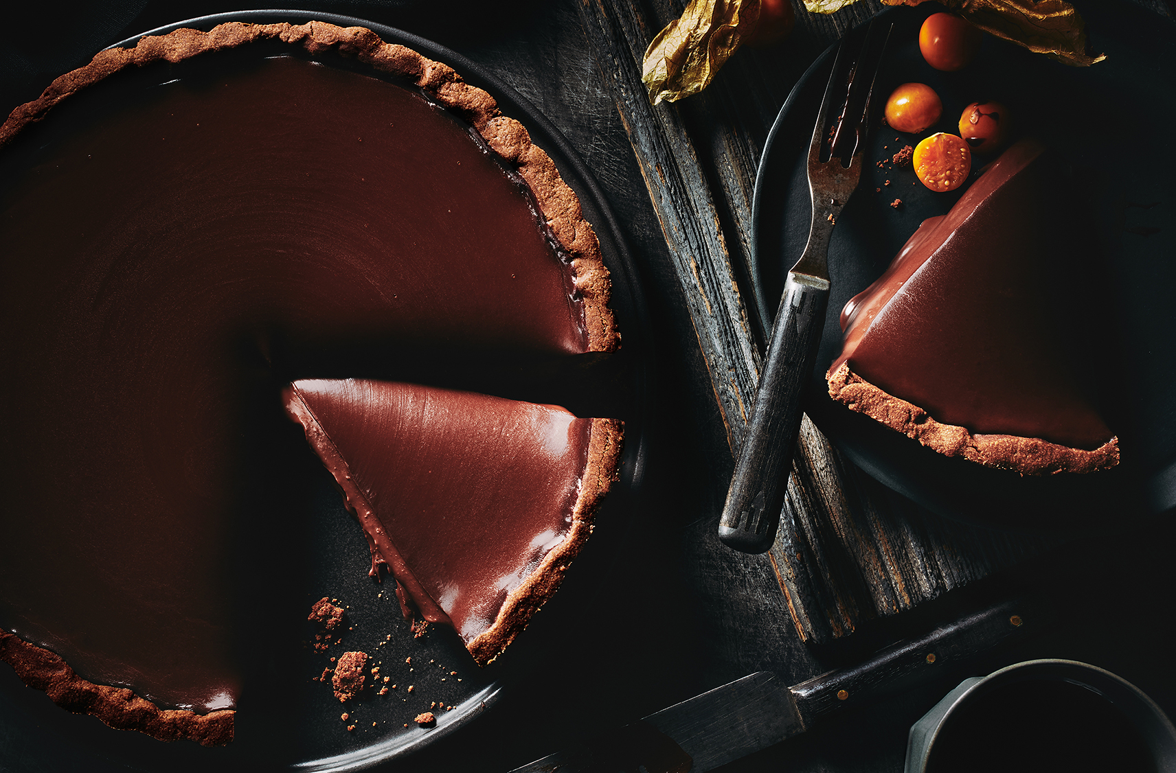 dark chocolate mint truffle tart in a tart dish.  two slices have been cut out of it ready to serve