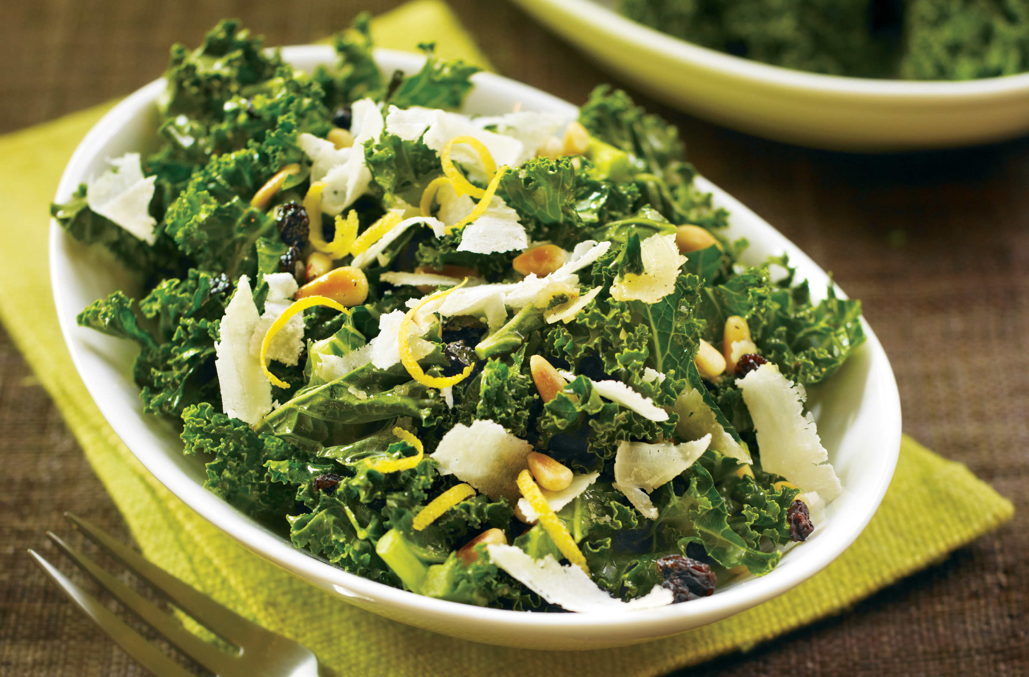 Une salade de chou frisé avec pignons, raisins de Corinthe, zeste de citron et copeaux de pecorino dans un bol